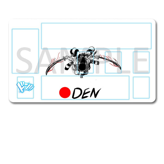 A white rectangular card or mat with printed blue grid lines, a central black-and-white illustrated character, a small blue hand icon, and the text 'DEN' next to a red circle, shown above a black drawstring pouch on a white background.