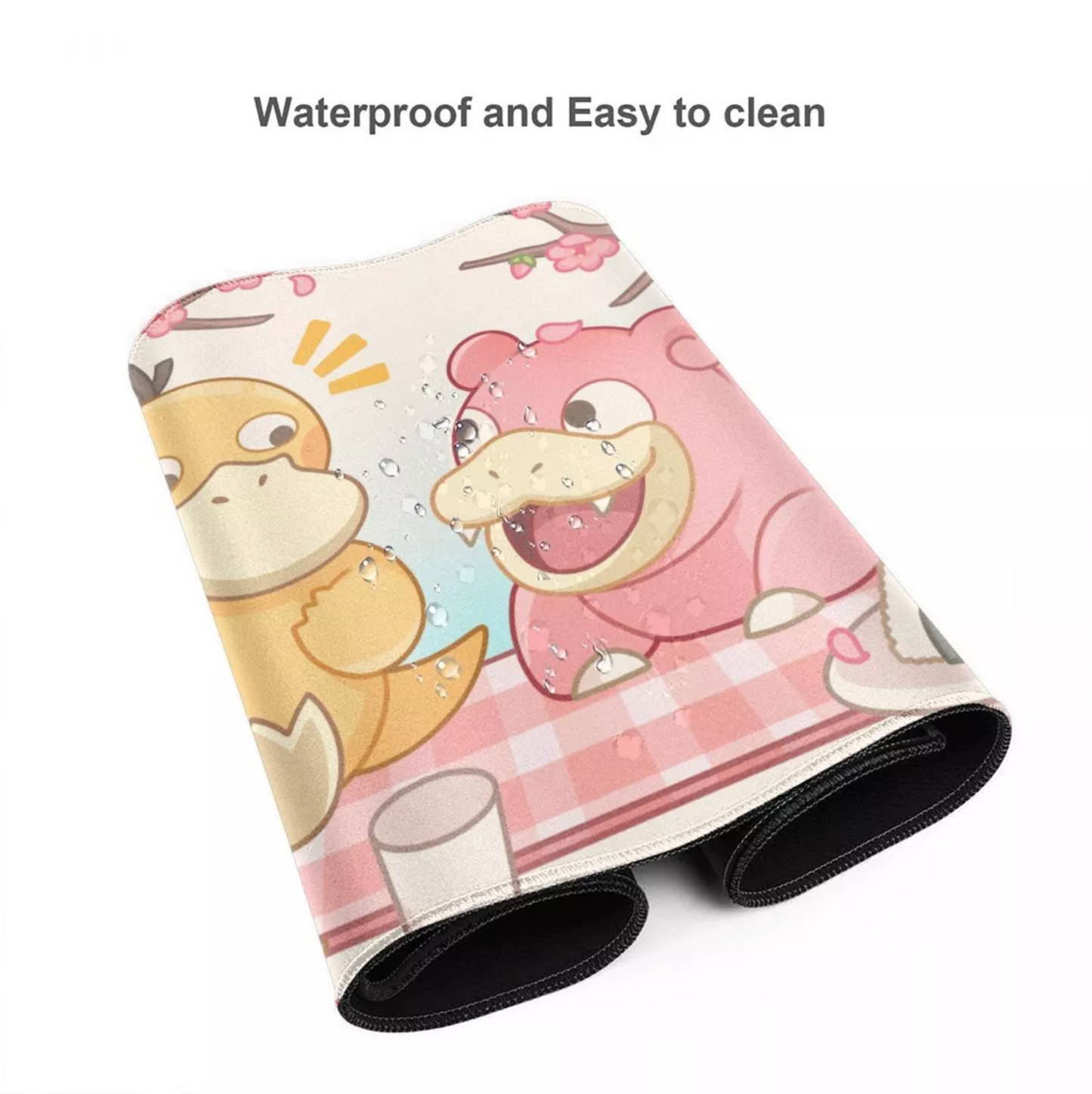 A rolled-up protective mat or towel featuring a cute cartoon print of a pink bear and a yellow duck on a pink checkered tablecloth, with water droplets shown on the surface. Text above reads 'Waterproof and Easy to clean'.