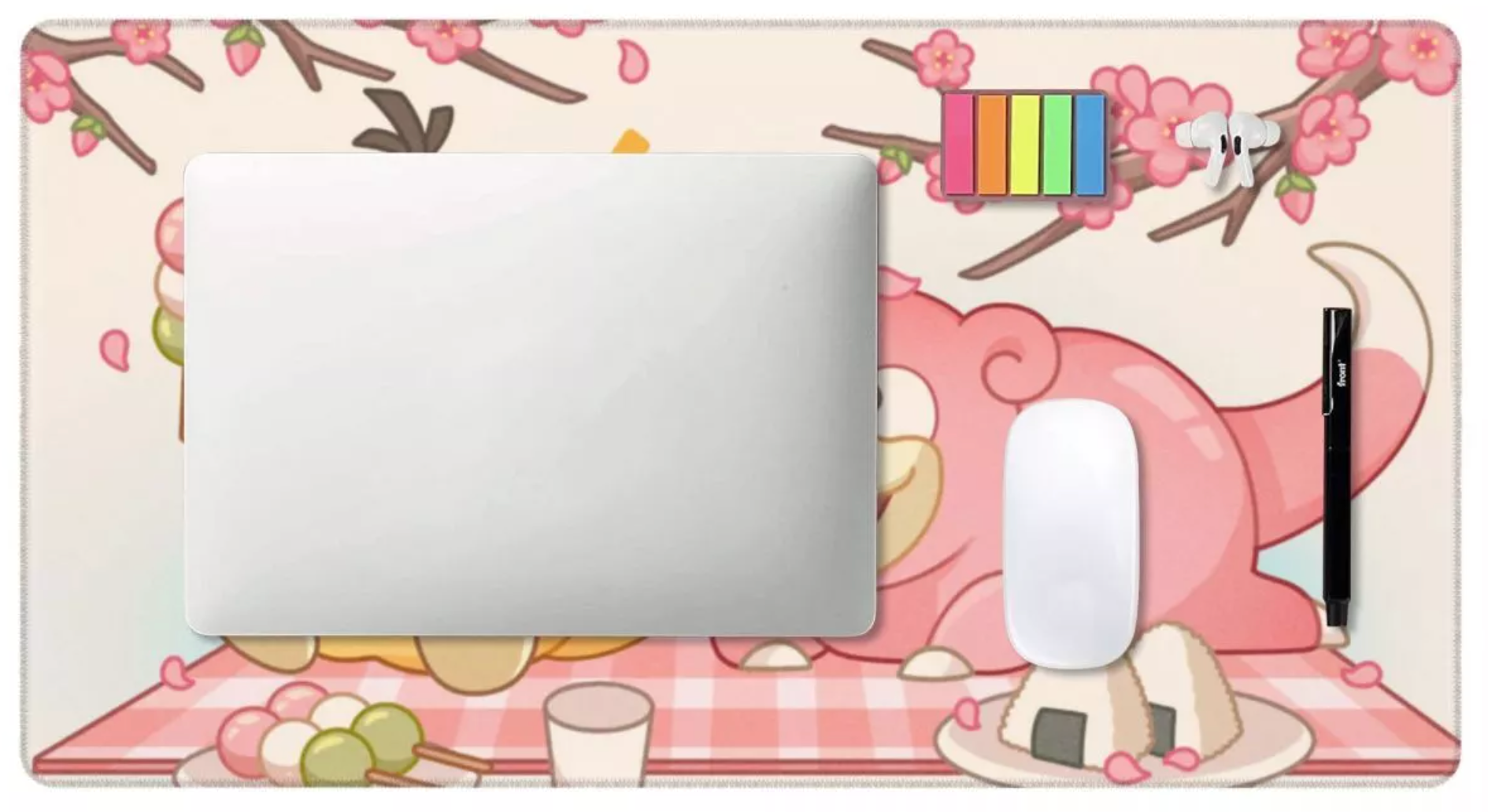 A rectangular desk mat with a pink and beige cherry blossom picnic illustration, shown with a silver laptop, white mouse, and black stylus on top against a white background.