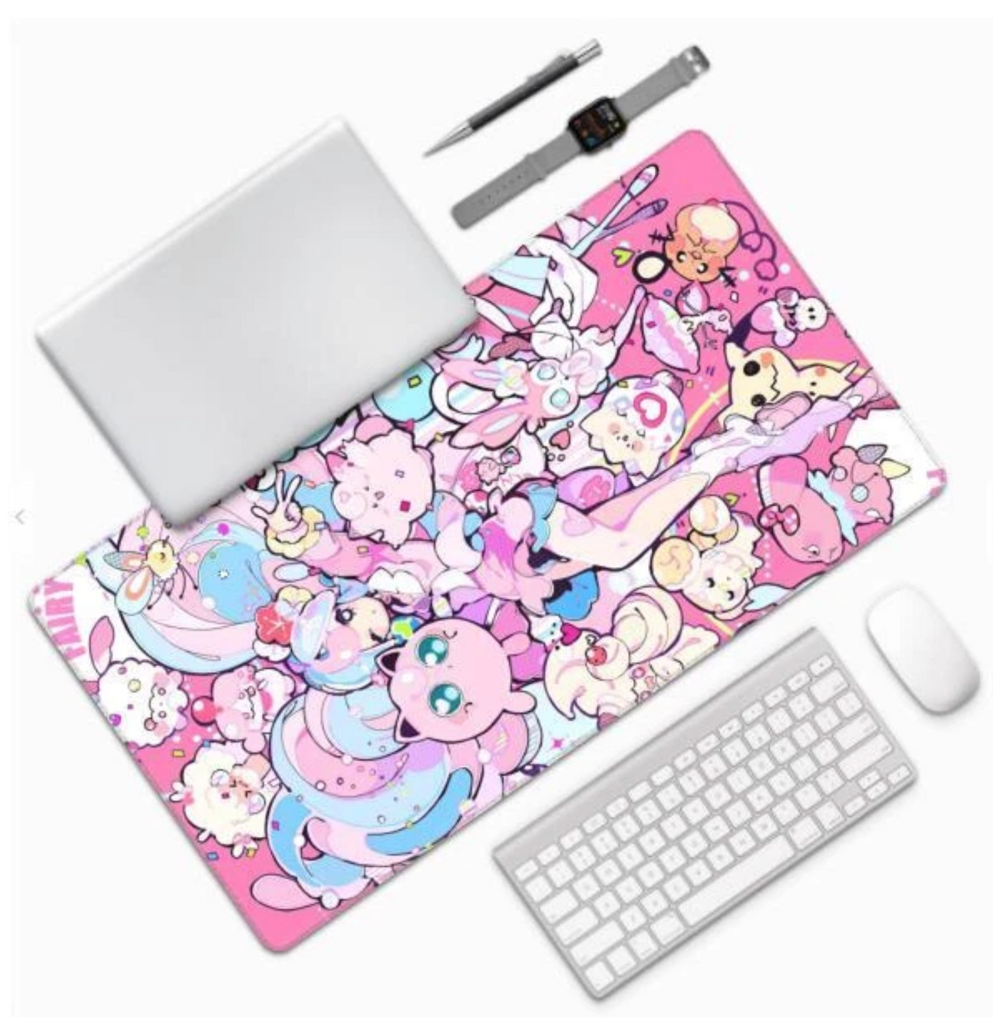 A large rectangular desk mat with a colorful pink cartoon character print, shown on a white background with a laptop, keyboard, mouse, pen, and smartwatch around it.