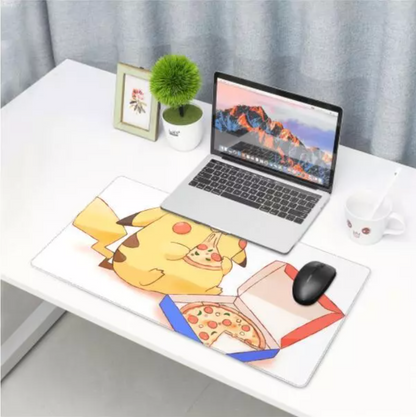 A large desk mat featuring a cartoon Pikachu holding a slice of pizza next to an open pizza box, shown on a white desk with a laptop, mouse, mug, and small plant in a home office setting.