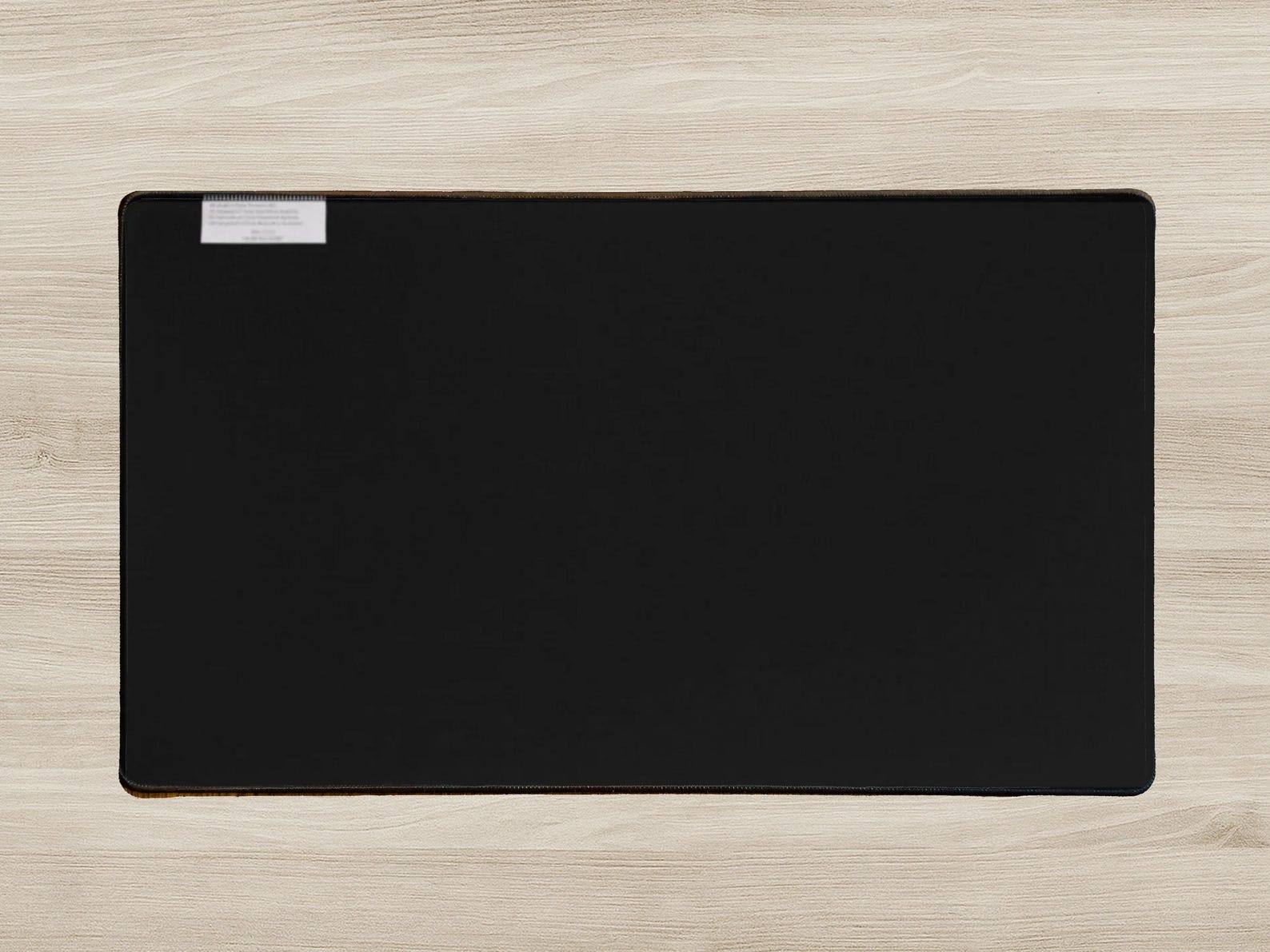 Black desk mat on a light wood surface