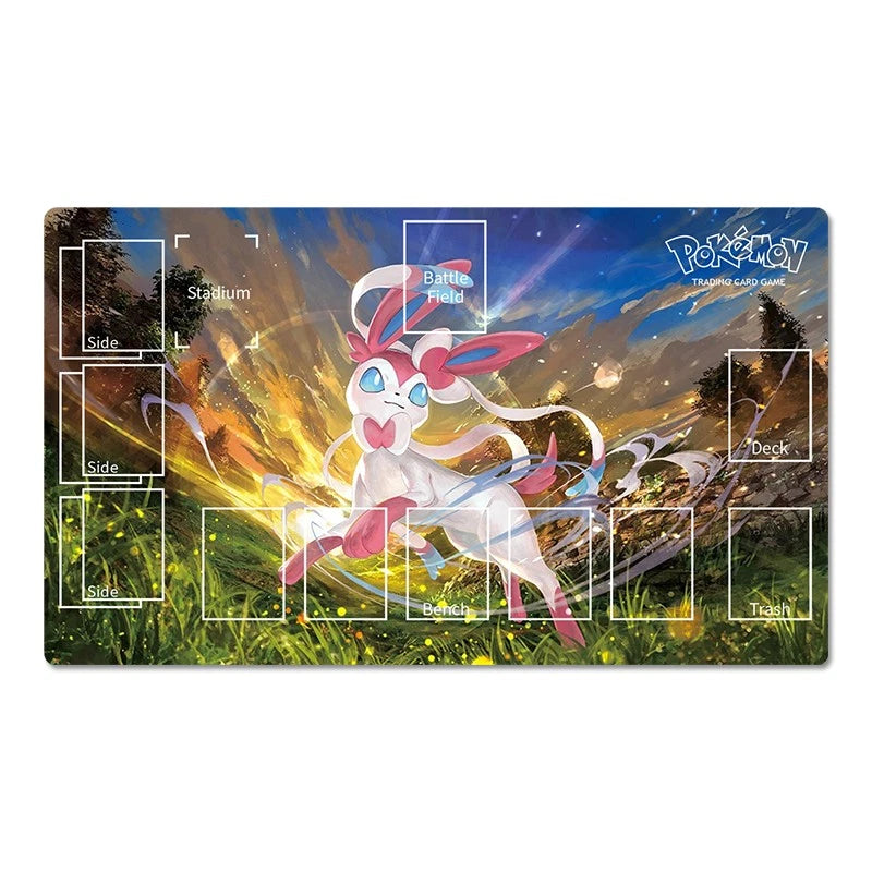 A rectangular Pokémon trading card game playmat featuring a colorful fantasy illustration of a white and pink Pokémon in a grassy landscape at sunset, with printed game area labels such as Battle Field, Deck, Stadium, and Team.